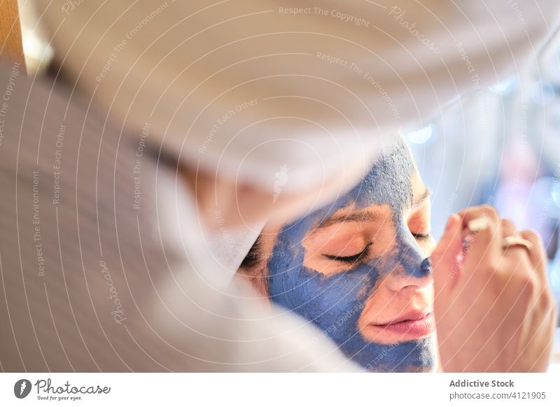 Unbekannte Frau trägt Tonmaske auf das Gesicht einer glücklichen Frau auf Frauen bewerben heimwärts Pflege Hautpflege zufrieden Glück Zusammensein Kälte räkeln