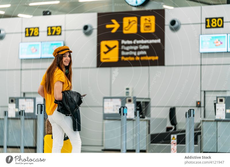 Fröhliche junge Frau, die sich vor der Abreise am Flughafen verabschiedet einchecken reisen Abschied Verabschiedung farbenfroh Abheben lassen Freude trendy