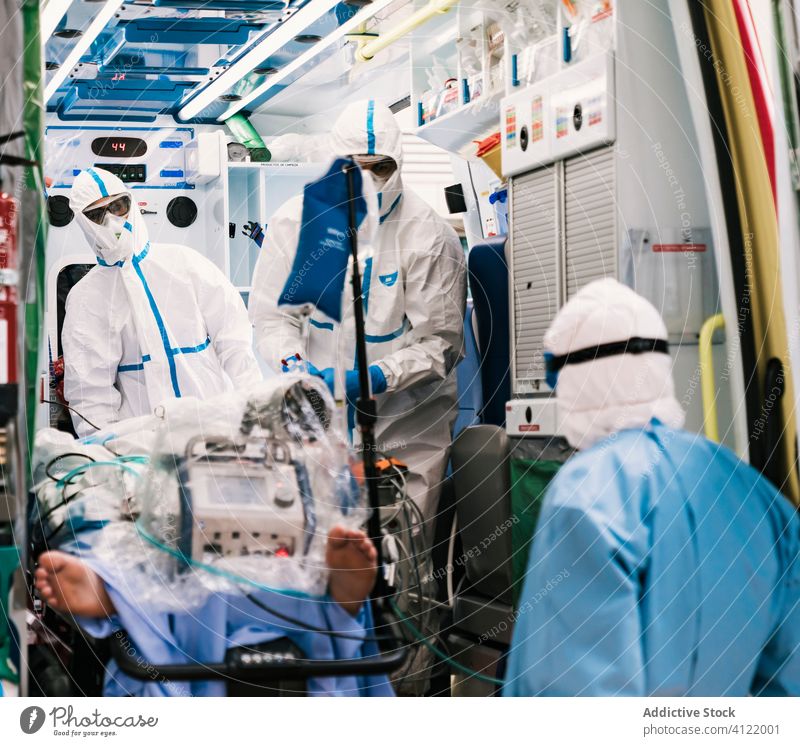 Innenraum eines Krankenwagens mit Ärzten im Schutzanzug Arzt Menschengruppe Uniform Gerät geduldig Dienst PKW Krankenhaus Klinik professionell Arbeit Fahrzeug