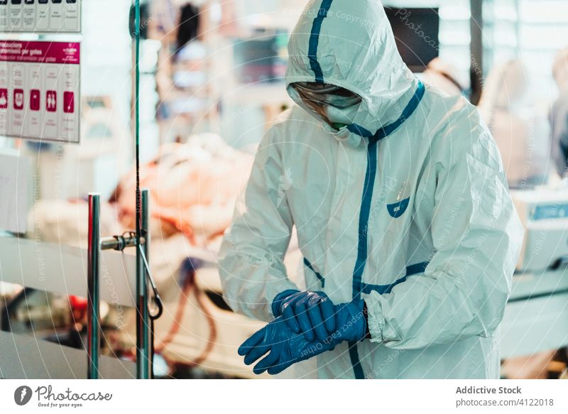 Arzt in Schutzkleidung zieht in der Klinik Handschuhe an Uniform Mundschutz Latex Chirurgie Krankenhaus Spezialist behüten steril Gesundheitswesen Leckerbissen