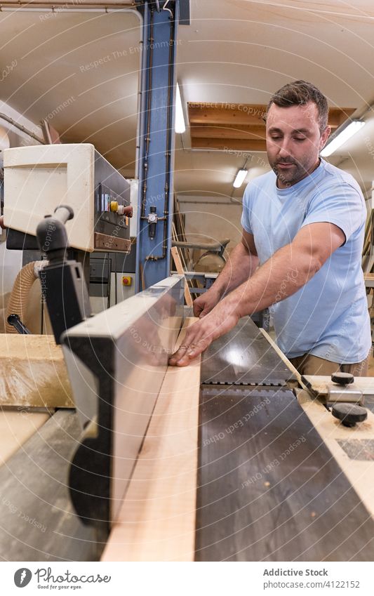 Aufmerksamer Erwachsener sägt Holz im Arbeitsraum Mann Säge Maschine Nutzholz Schreinerei geschnitten Zimmerer Schiffsplanken Werkstatt Tischler Gerät