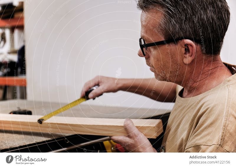 Aufmerksamer Handwerker mit Maßband bei der Arbeit mit Holz in der Tischlerwerkstatt Messung Kunsthandwerker Klebeband Arbeiter Kontrolle Schreinerei achtsam
