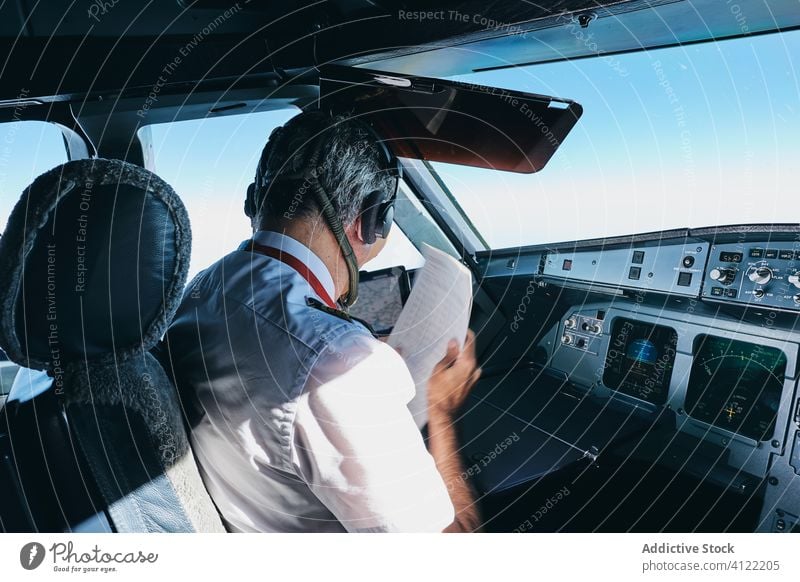 Kapitän überprüft Flugdokument im Flugzeug-Cockpit Pilot Schriftstück lesen vorbereiten prüfen Mann Flieger männlich modern Fluggerät Ebene Verkehr Luftverkehr