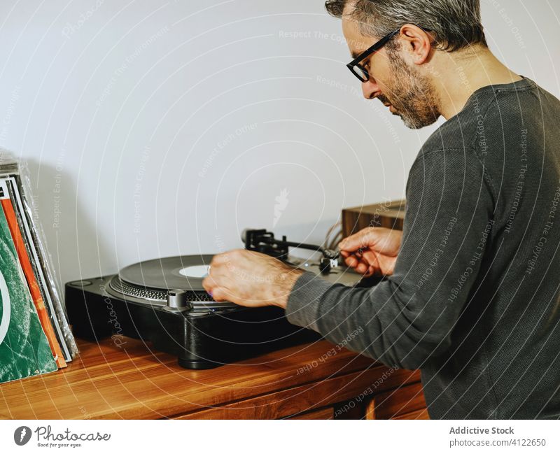 Gut aussehender Mann hört Musik auf einem Schallplattenspieler Vinyl Aufzeichnen Scheibe Plattenteller Spieler retro altehrwürdig Nostalgie zuhören Kälte