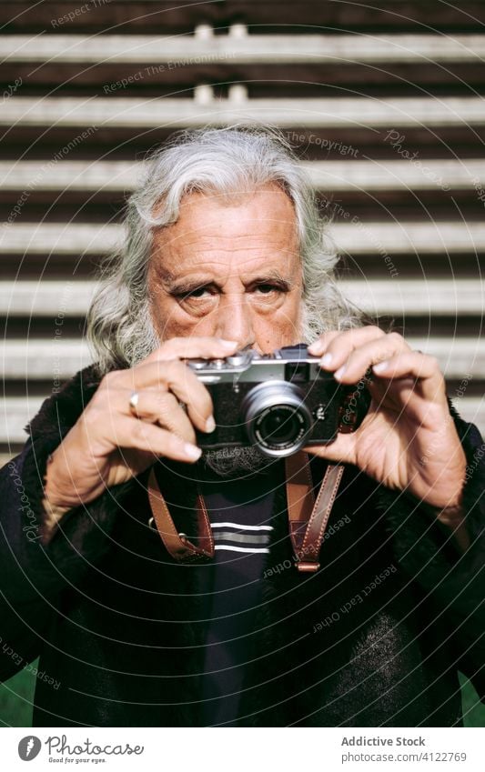 Älterer stilvoller Mann, der Fotos mit einer alten Kamera macht Senior Stil fotografieren Großstadt altehrwürdig retro trendy Fotoapparat Fotograf männlich
