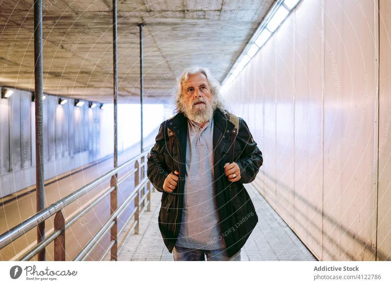 Älterer Mann geht auf dem Gehweg im Tunnel Bürgersteig Stollen unterirdisch reisen Senior schlendern Fußgänger reif gealtert führen Tourist Spaziergang urban