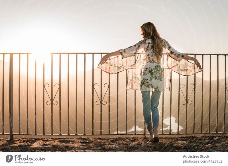 Anonyme Frau steht in der Nähe des Metallzauns und genießt die malerische Aussicht bei Sonnenuntergang Tourist Aussichtspunkt Zaun bewundern Terrasse