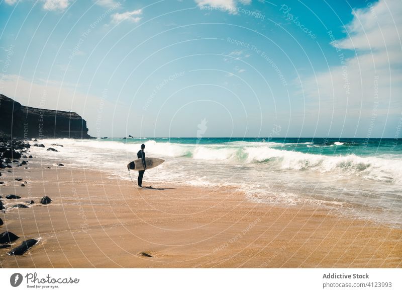 Unbekannter Surfer am wogenden Meer Mann Surfbrett Strand MEER winken Resort Hobby Fuerteventura Spanien Kanarische Inseln sonnig tagsüber Wasser Ufer Küste