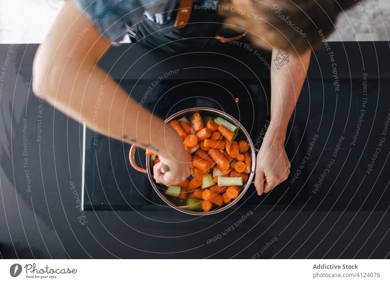 Frau kocht Gemüsesuppe in der Küche Abendessen Koch Möhre Herd rühren Suppe Kochtopf Schürze vorbereiten Lebensmittel modern Küchengeräte Rezept heimwärts