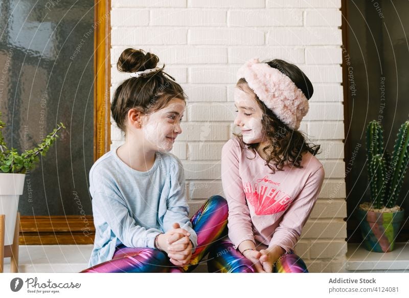 Glückliche kleine Schwestern mit lustigem Wellness-Tag zu Hause Kinder Spaß haben Gesichtsmaske Lachen gleich Zusammensein heimwärts spielerisch Hautpflege