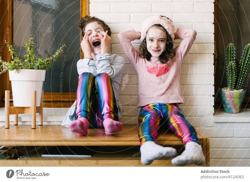 Glückliche kleine Schwestern mit lustigem Wellness-Tag zu Hause Kinder Spaß haben Gesichtsmaske Lachen gleich Zusammensein heimwärts spielerisch Hautpflege
