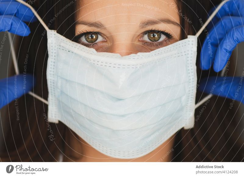 Frau mit Schutzmaske und Handschuhen bei der Arbeit zu Hause Coronavirus Mundschutz behüten COVID Sicherheit Pandemie Risiko Krankheit ernst Ausbruch angezogen