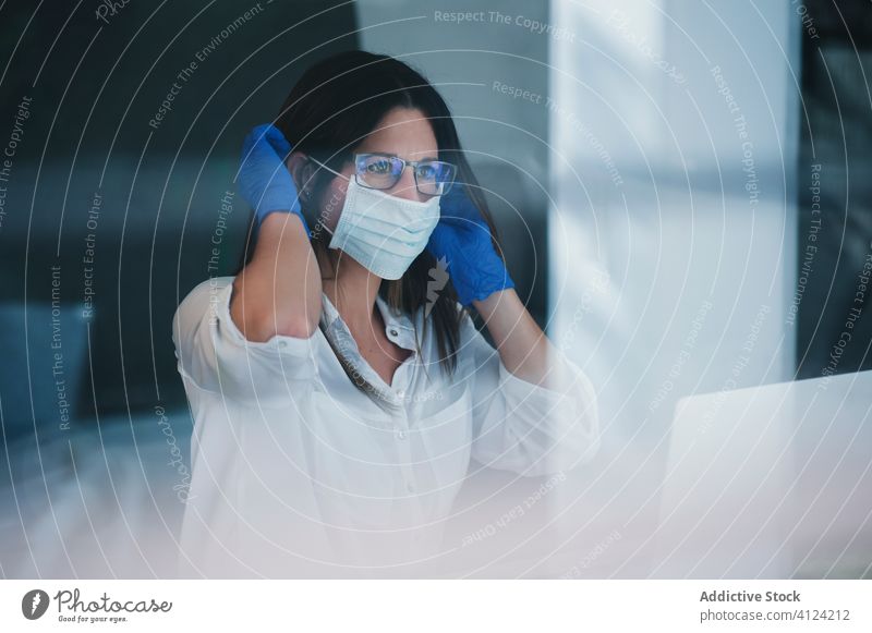 Frau mit Schutzmaske und Handschuhen bei der Arbeit zu Hause Coronavirus Mundschutz behüten COVID Sicherheit Pandemie Risiko Fenster Krankheit ernst Ausbruch