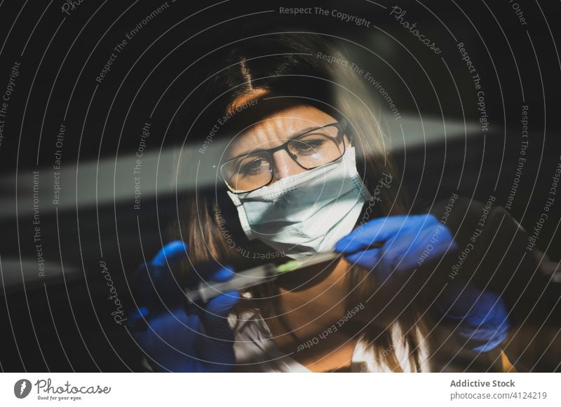 Frau benutzt Spritze während der COVID 19-Pandemie Coronavirus Mundschutz Diagnostik Handschuh behüten Arzt Sicherheit Risiko Krankheit Krankenpfleger ernst