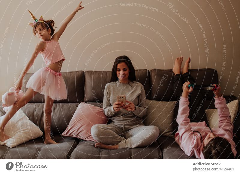 Mutter und Kinder entspannen sich auf dem Sofa Kälte heimwärts Tanzen Smartphone benutzend spielen Videospiel Frau Sohn Tochter Mädchen Teenager Eltern