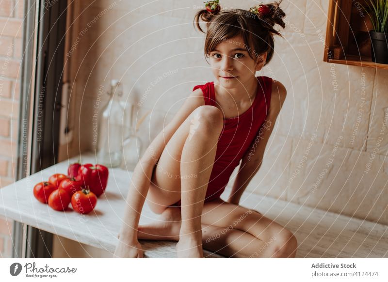 Kleines Mädchen sitzt auf der Theke mit Tomaten und rotem Pfeffer Küche Paprika Gesundheit Lebensmittel hell Vegetarier niedlich Barfuß Body heimwärts sitzen