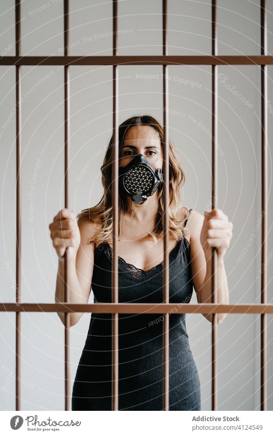 Frau mit Beatmungsmaske hinter Gittern Mundschutz Zaun Einsperrung Isolation COVID Coronavirus Konzept Bar verhindern Gefängnis Schloss behüten einlochen