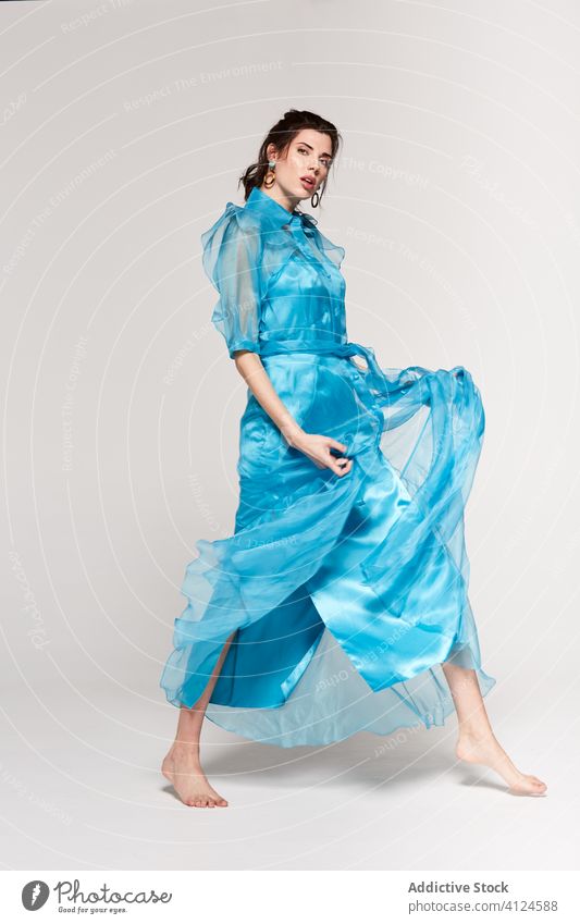 Junge stilvolle Dame in blauem Kleid steht im Studio und schaut nach unten Frau Atelier Stil Mode posierend attraktiv lange Haare jung trendy Farbe durchsichtig