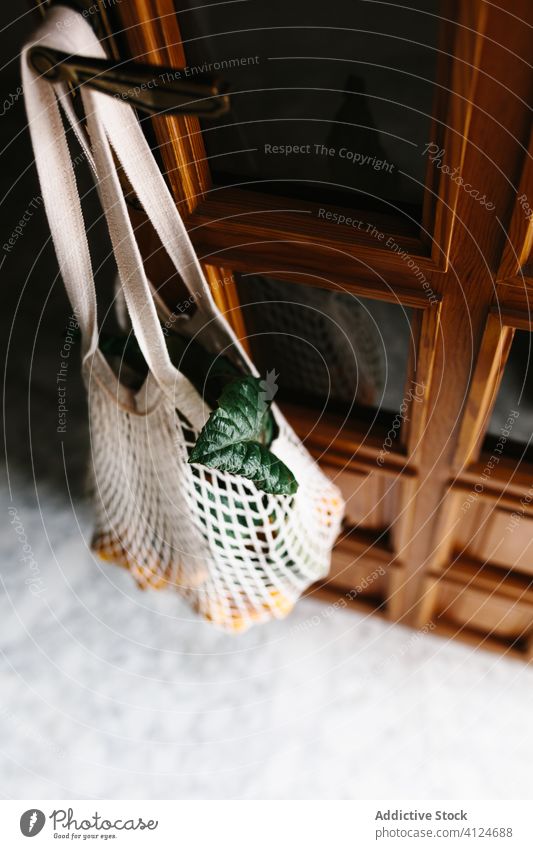 Schnur-Einkaufstasche mit Nispero-Früchten an der Türklinke umweltfreundlich nispero loquat Baumwolle Sack Raum hängen dunkel Licht Knauf frisch lecker