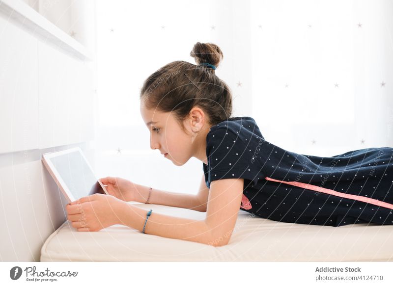 Positives Mädchen, das ein Tablet benutzt, während es sich zu Hause im Bett ausruht Tablette heimwärts ruhen Browsen soziale Netzwerke Teenager Kälte positiv
