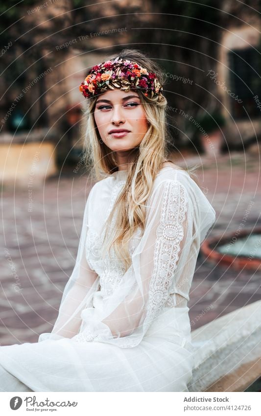 Blonde Braut ruht sich im Hof aus Frau ruhen Hochzeit Kleid Totenkranz Blume jung elegant durchscheinend geblümt Gelassenheit Veranstaltung feiern sitzen ruhig