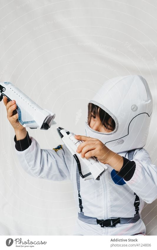 Kind in Astronautenkostüm und Helm spielt mit Spielzeugraketen Tracht Schutzhelm spielen Rakete spielerisch Spaß haben Raumschiff Raumanzug Uniform