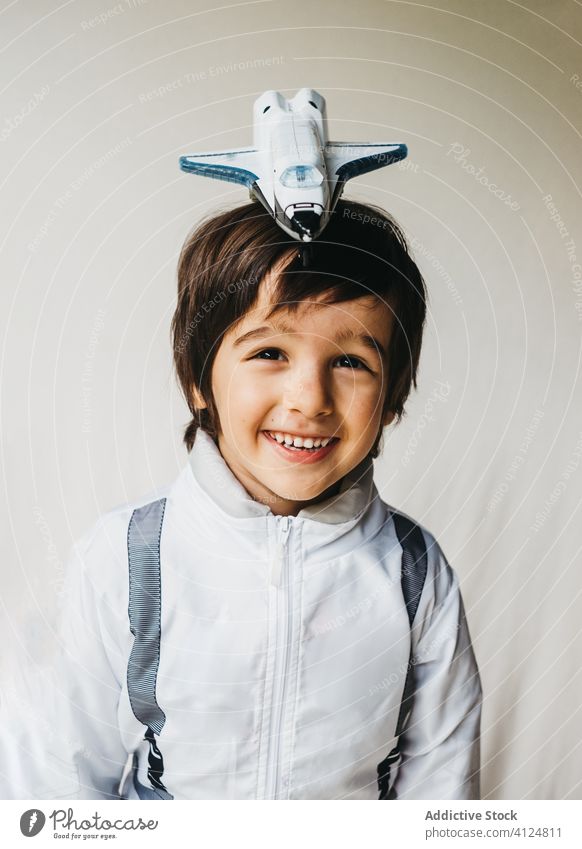 Anbetungswürdiger Junge im Kosmonautenkostüm auf weißem Hintergrund Tracht bezaubernd Raumfahrer Spielzeug Raumschiff positiv Kind Astronaut Spaß haben
