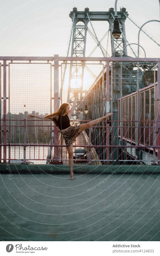 Frau tanzt barfuß auf einer Brücke in der Stadt Tanzen Großstadt Gleichgewicht auf Zehenspitzen Anmut Tänzer industriell üben Choreographie schlank beweglich