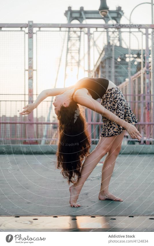 Schlanke flexible Frau tanzt auf einer Brücke in der Stadt Tanzen beweglich Anmut Großstadt Rückbiegung Tänzer schlanke Barfuß jung lässig Rock Outfit anhaben