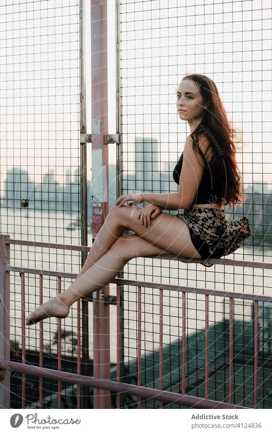 Junge Tänzerin sitzt auf dem Metallgeländer der Brücke Frau Anmut Gleichgewicht industriell urban Stadtbild Reling Barfuß jung ruhig Gelassenheit Windstille
