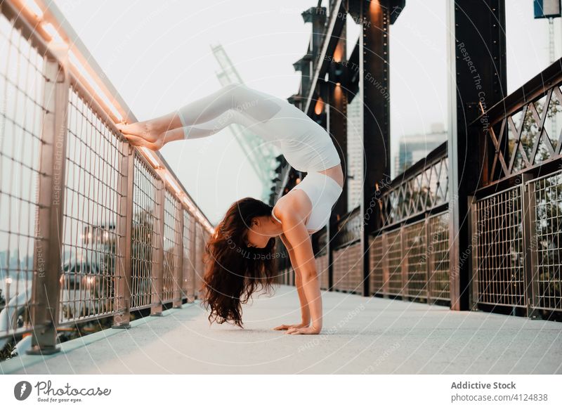 Fit Frau übt Yoga auf Brücke urban Handstand üben beweglich Asana Skorpion-Handstand Übung passen Rückbiegung Großstadt schlank Gleichgewicht