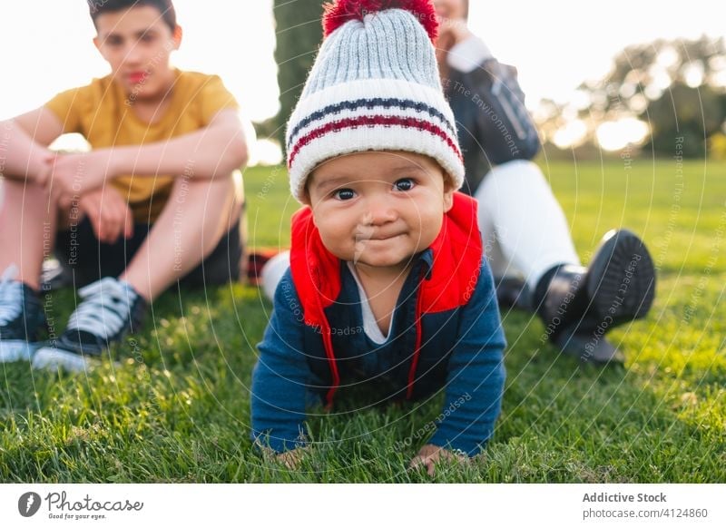 Glückliches kleines Kind krabbelt auf grünem Gras krabbeln Familie Kleinkind Wiese Lächeln Natur niedlich ethnisch Landschaft Freude Baby heiter Kindheit Eltern