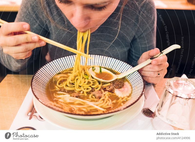Junge Frau isst Ramen im Cafe essen Café Tradition Japanisch jung Löffel Essstäbchen Schalen & Schüsseln Speise Tisch geschmackvoll Küche Lifestyle Restaurant