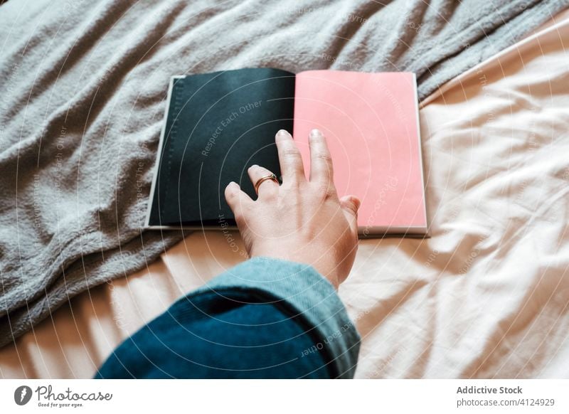 Neugierige Frau nimmt aufgeschlagenes Buch vom Bett heimwärts Notebook Hand Leseratte Kälte Wahl Journal Erholung heimisch offen Schlafzimmer unterhalten