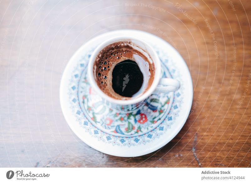 Eine Tasse frischen türkischen Kaffee Türkisch schwarz aromatisch Untertasse Orientalisch heiß Tradition Muster Tisch hölzern Getränk trinken Kultur lecker