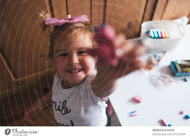 Fröhliches kleines Mädchen zeigt Knetmasse in die Kamera Spielzeug Modellierung Ton manifestieren Ergebnis handgefertigt zeigen Glück stolz charmant heimwärts