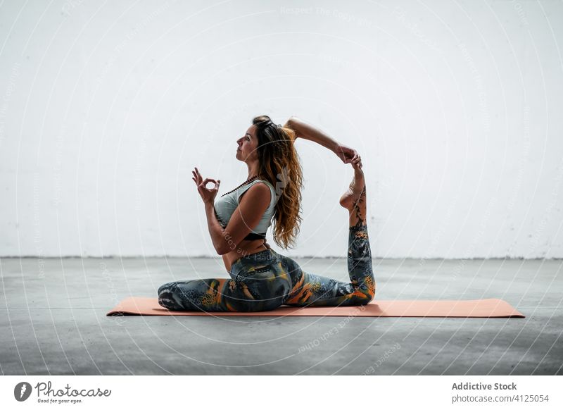 Flexible Frau macht Yoga in King Pigeon Pose Kingtaube beweglich eka pada rajakapotasana Asana Mudra üben Unterlage sitzen Sportbekleidung aktive Kleidung
