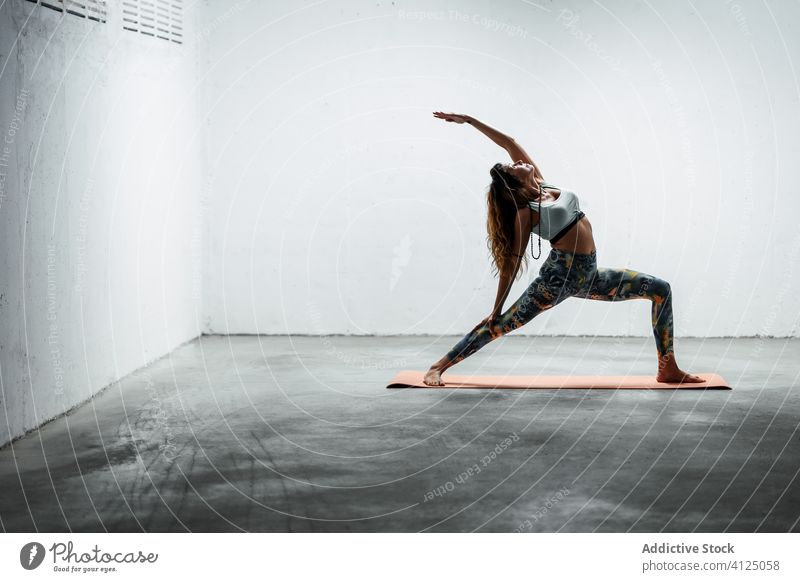 Schlanke Frau macht Yoga in umgekehrter Kriegerpose Gleichgewicht Rückwärtskrieger üben Windstille Pose schlanke Asana Unterlage beweglich stehen Stock