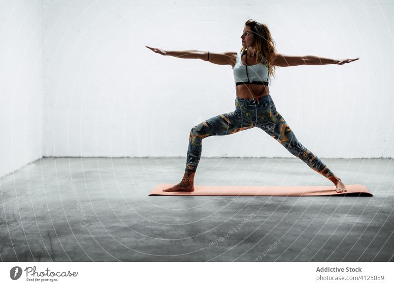 Schlanke Frau macht Yoga in Krieger zwei Pose Gleichgewicht üben Windstille schlanke Asana Unterlage beweglich stehen Stock virabhadrasana Sportbekleidung