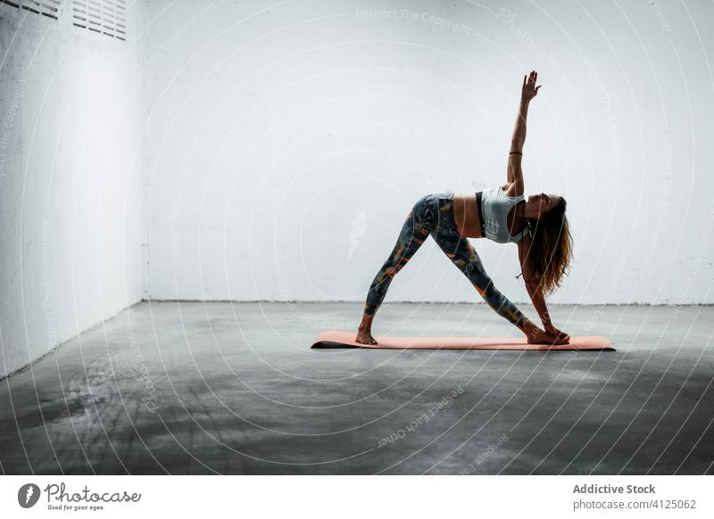 Schlanke Frau beim Yoga in erweiterter Dreieckspose Gleichgewicht erweitertes Dreieck üben Windstille Pose schlanke utthita trikonasana Asana Unterlage