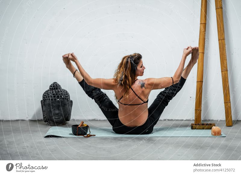 Flexible Frau beim Yoga in Bootspose Boot-Pose navasana Dehnung Sportbekleidung üben beweglich Erwachsener Unterlage sitzen Gesundheit Wellness Harmonie passen