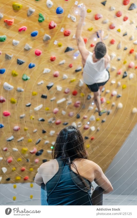 Sportlerin betrachtet Kletterer an der Wand im Fitnessstudio Aufsteiger Team zuschauen beobachten Ausbilderin Trainer Stock aktiv ruhen muskulös