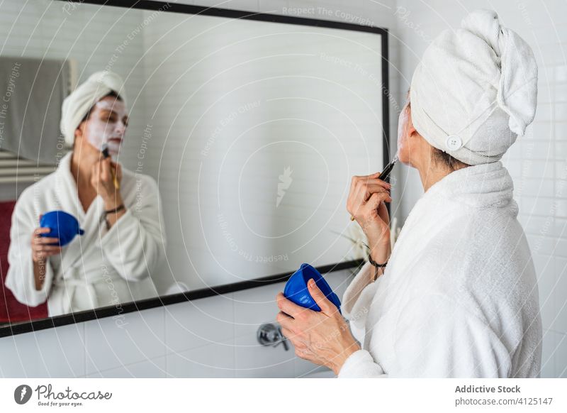 Frau trägt kosmetische Maske auf Gesicht auf bewerben Gesichtsbehandlung Mundschutz Feuchtigkeit Kosmetik Bürste Hautpflege Hydrat Kosmetologie Bad liquide