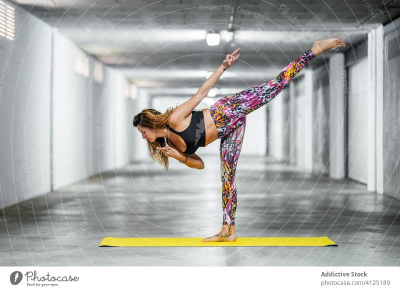 Erfahrene Frau, die fortgeschrittene Yoga-Asanas praktiziert üben Krieger drei Pose Garage positionieren Herausforderung Gleichgewicht Körperhaltung Wellness