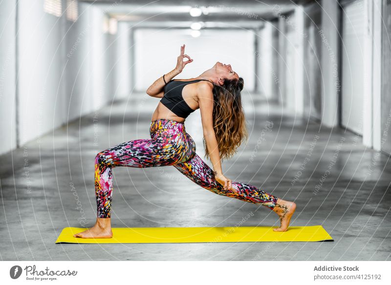 Erfahrene Frau, die fortgeschrittene Yoga-Asanas praktiziert üben Rückwärtskrieger Pose Garage positionieren Herausforderung Körperhaltung Wellness abstützen