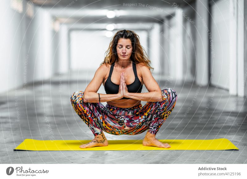 Ruhige Frau meditiert in Malasana-Pose Yoga üben meditieren Asana malasaña Girlande positionieren Gleichgewicht Windstille Garage ruhig Wellness Lifestyle