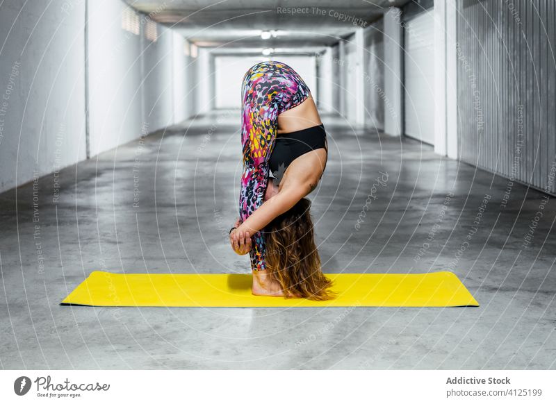 Erfahrene Frau, die fortgeschrittene Yoga-Asanas praktiziert üben stehende Vorwärtsbeuge Pose Garage positionieren Herausforderung Körperhaltung Wellness