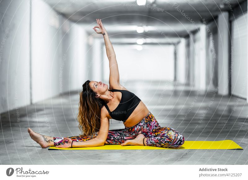 Frau praktiziert Yoga auf der Matte üben mit dem Kopf zum Knie gedreht parivrtta janu sirsasana Pose Unterlage Körperhaltung positionieren Garage Gleichgewicht