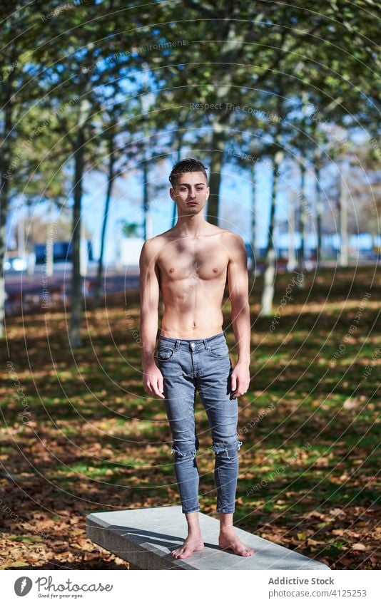 Shirtless fit Mann im Park stehen ohne Hemd selbstbewusst Tänzer Anmut Athlet Bauchmuskeln passen Barfuß nackter Torso Jeanshose Herbst Gesundheit Motivation