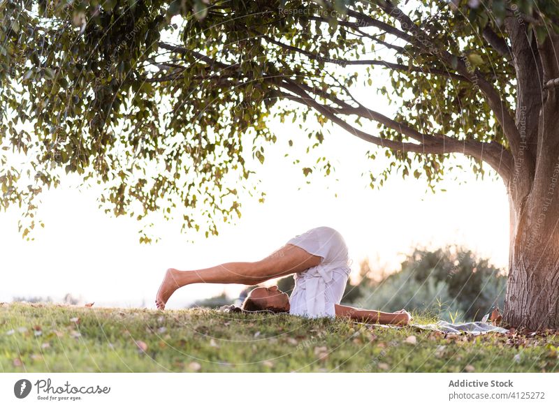 Mann meditiert auf grüner Wiese mit üppigem Baum Yoga meditieren Harmonie Sommer Rasen Gras weiß Park im Freien Windstille Gesundheit Lifestyle